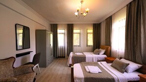 Een hotelkamer met twee bedden, een zithoek met een bank, een spiegel en een kroonluchter.
