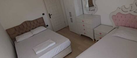Une chambre avec deux lits, une commode, un miroir et un ventilateur de plafond.