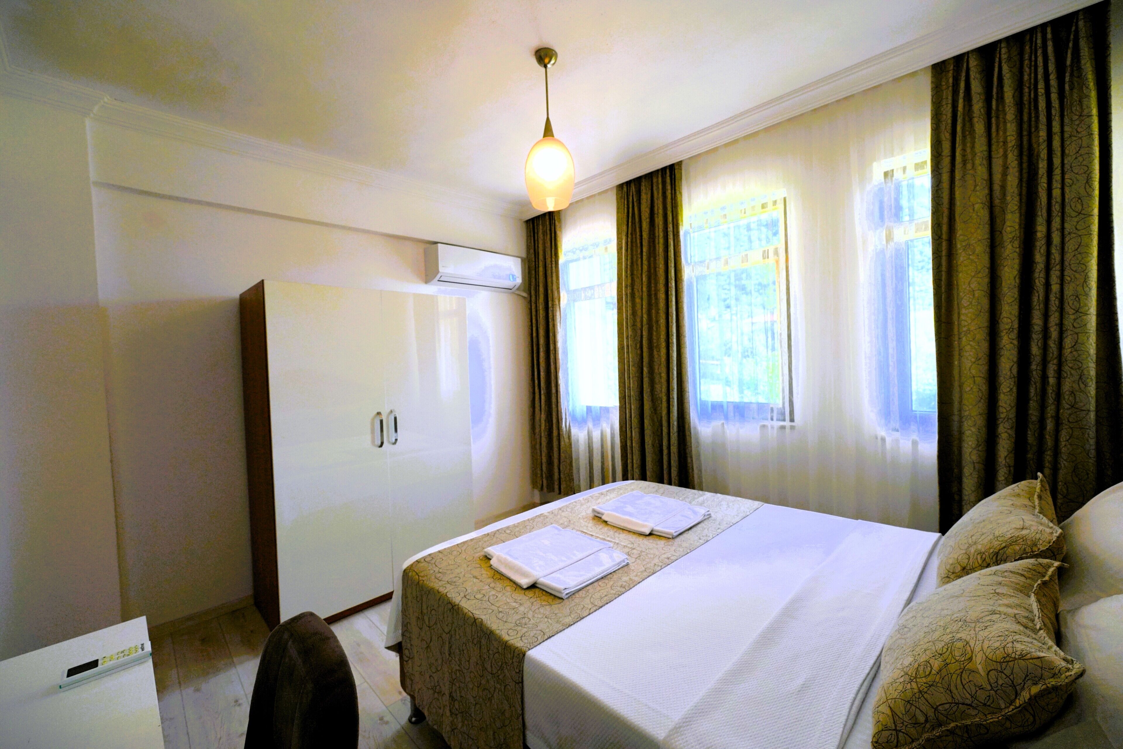 A hotel room with a bed, a desk, and a wardrobe.