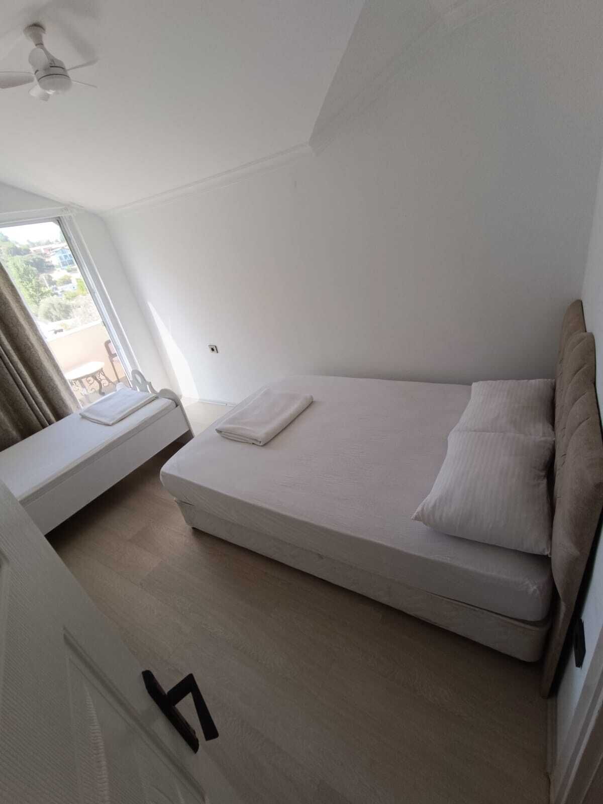 A bedroom with a bed, a window, and a ceiling fan.