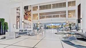 Um lobby amplo com várias áreas de estar, teto alto e grandes janelas que oferecem vista para o exterior.