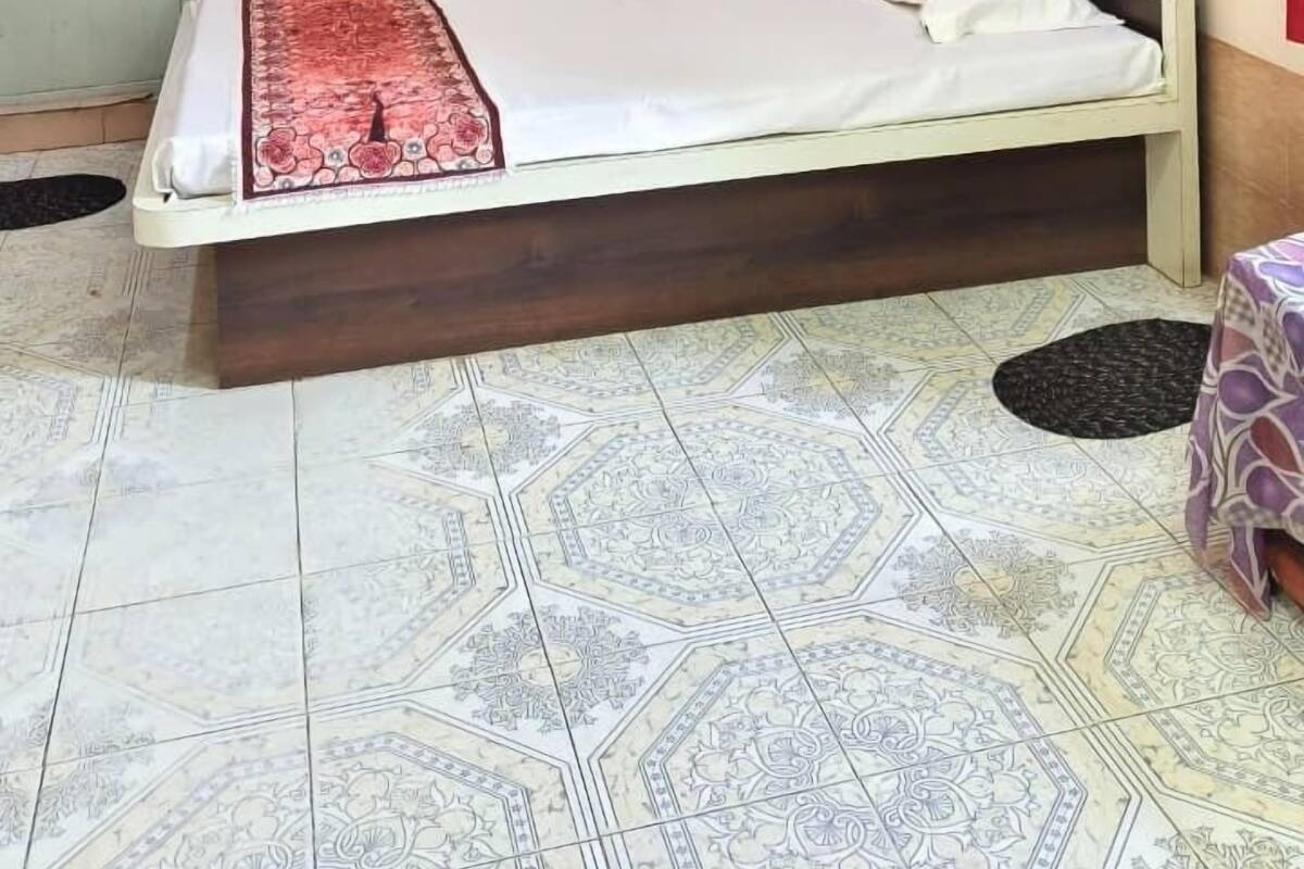 Un dormitorio con cama, ventilador de techo, aire acondicionado, un tapiz decorativo y una cortina roja.