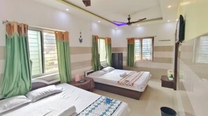 A hotel room with two beds, a ceiling fan, a flat-screen TV, and a window with curtains. - Maa Durga Guest Inn (Digha)