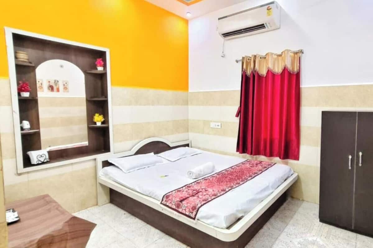 Una habitación de hotel con una cama, un armario, una estantería con adornos y un espejo.