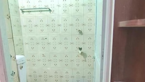 Une petite salle de bain avec des toilettes, un seau bleu et un espace douche.