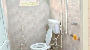 Une petite salle de bain avec des toilettes, un seau bleu et un pommeau de douche.
