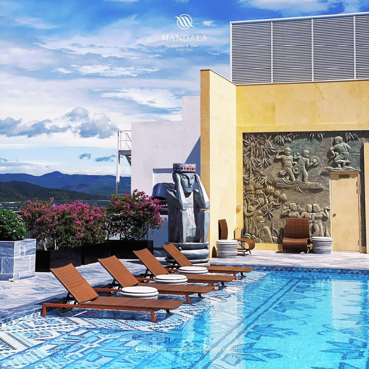 A rooftop pool area with lounge chairs, a stone sculpture, and a mural.
