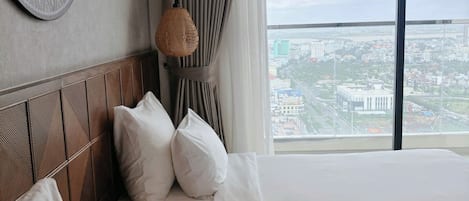 A hotel room with two beds, a large window with a city view, a patterned wall decoration, and a textured lamp.
