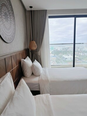 Ein Hotelzimmer mit zwei Betten, einem großen Fenster mit Stadtblick, einer Wanddekoration mit Muster und einer lamellenartigen Lampe.