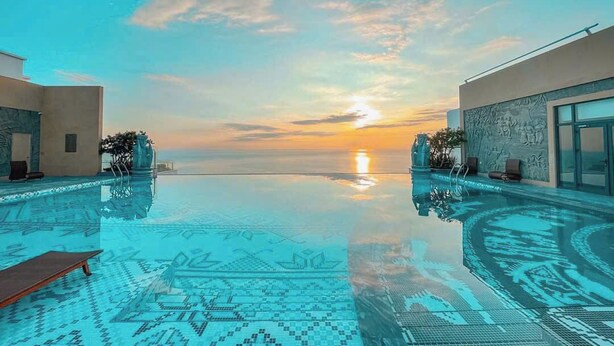A infinity pool with a sunset view, surrounded by modern architecture. - APEC TUY HOA   - PHU YEN CONDOTEL (Tuy Hoa)