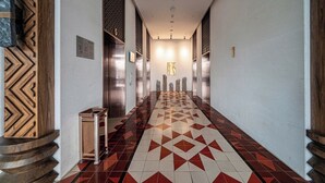 A hallway with patterned flooring, wooden paneling, and a central light fixture. - APEC TUY HOA   - PHU YEN CONDOTEL (Tuy Hoa)