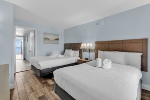 A hotel room with two beds, a wooden floor, a painting on the wall, and a view of the beach. - Landmark Resort Condos (Myrtle Beach)