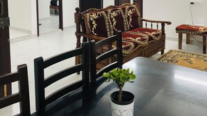A dining area with a table, chairs, a potted plant, and a sofa. - Virtus home stay  (Puducherry)