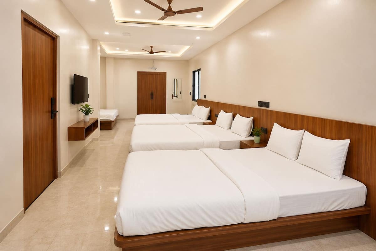 A hotel room with three beds, a TV, a ceiling fan, and a wooden headboard.