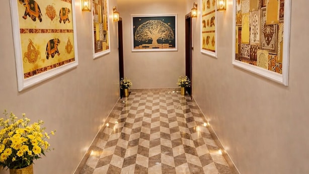Un couloir doté d’un revêtement de sol à motifs, d’œuvres d’art accrochées aux murs et d’appliques murales.