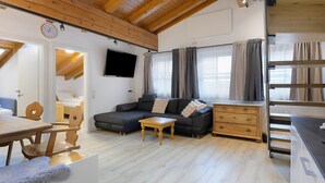 Una sala de estar moderna con un sofá, una mesa de centro de madera y un televisor montado en la pared.