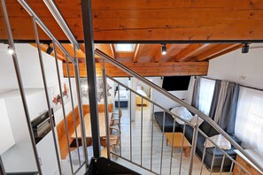 A modern interior with a staircase, wooden ceiling, and a living area with a sofa and table. - Apartment Goodlife B10 – 100 m to Kohlmaisbahn, Steps from Town Center (Saalbach)