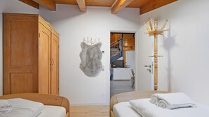 Un dormitorio con dos camas, un armario de madera y un perchero.