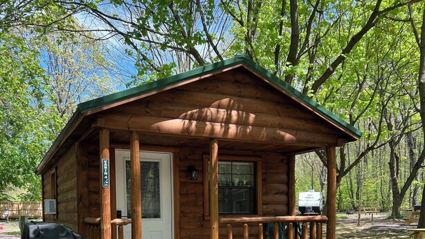 Eine Holzhütte mit Veranda, Picknicktischen und Grill.