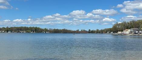 A lake with a boat, houses along the shore, and trees in the background.