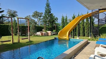 Una piscina al aire libre, sillones reclinables de piscina