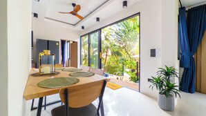 Un comedor moderno con una mesa de madera, sillas y un ventilador de techo.