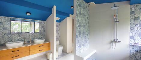 A modern bathroom with a blue ceiling, a large window, a sink, a toilet, and a shower.