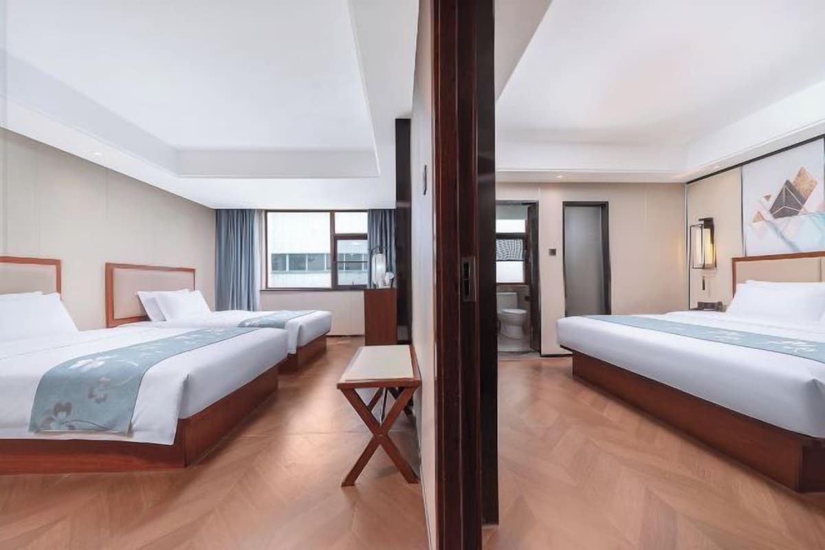 A hotel room with two beds, a small table, and a view of the city.
