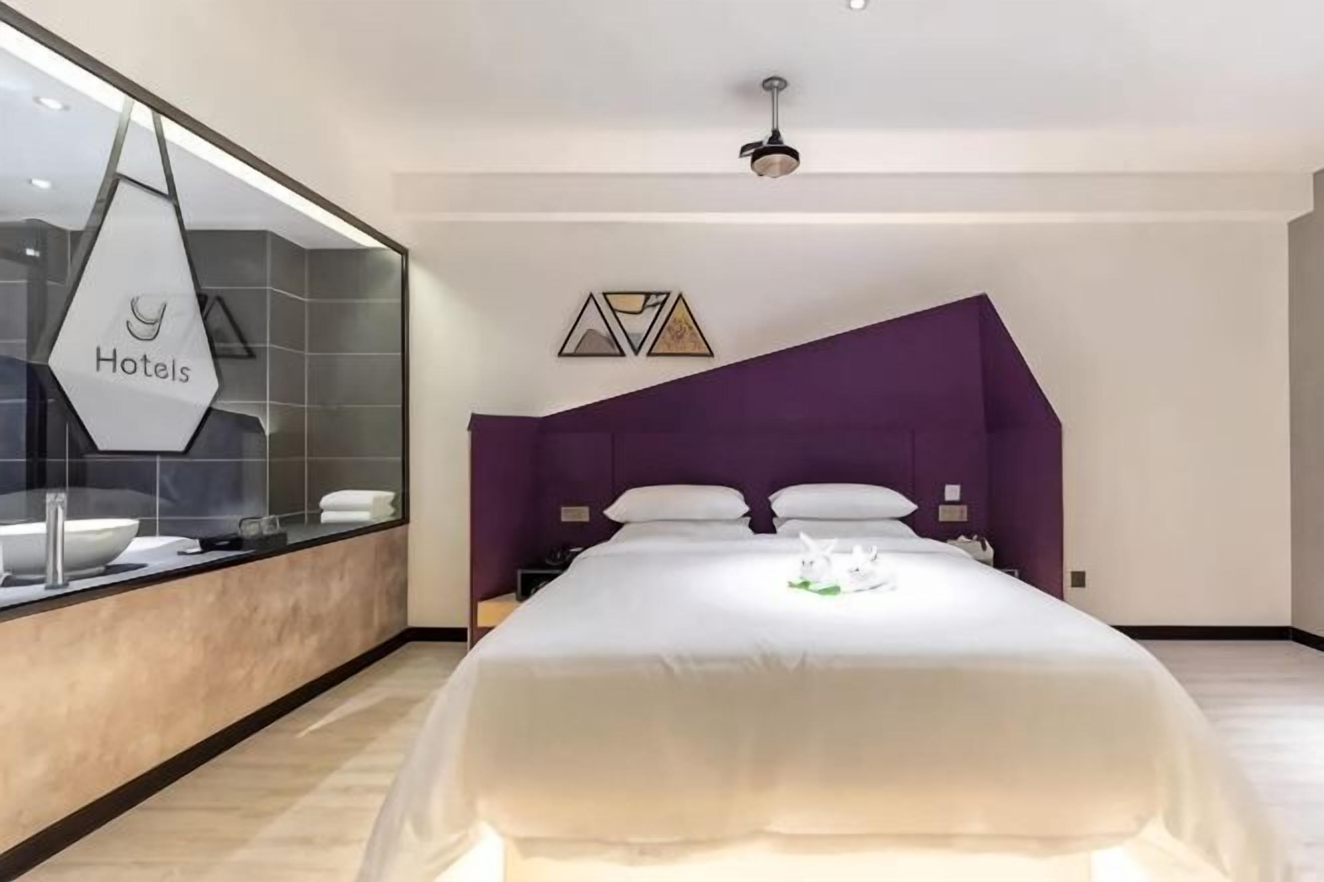 Una habitación de hotel moderna con una cama grande, una tocador con espejo y un diseño de pared geométrico único.