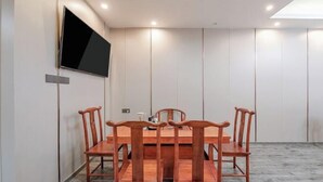 A conference room with a wooden table and chairs, a flat-screen TV mounted on the wall, and recessed ceiling lighting. - Wuling Hotel (Liuzhou High-speed Railway Station) (Liuzhou)