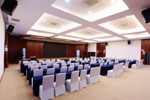 A conference room with rows of tables and chairs, a large screen, and a modern ceiling design. - Wuling Hotel (Liuzhou High-speed Railway Station) (Liuzhou)