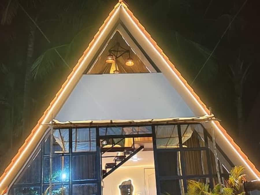 Edifici de forma triangular amb façana de vidre, una escala que condueix a un nivell superior i plantes en testos a l'entrada.