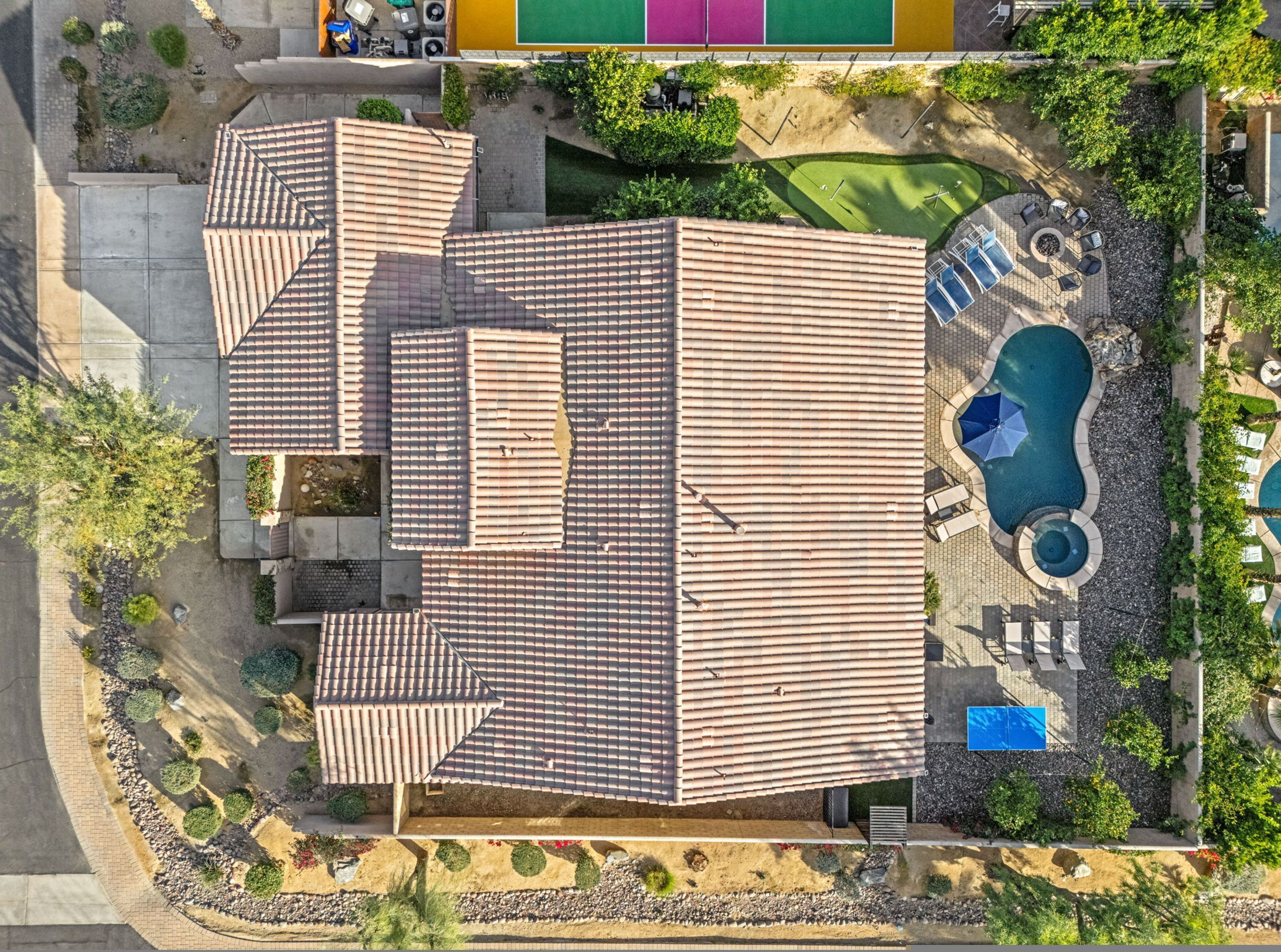 Vue aérienne d’une propriété dotée d’une grande piscine, de plusieurs espaces de détente en plein air et d’un jardin bien entretenu.