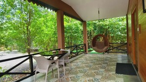 Un espacio al aire libre cubierto con suelo de baldosas, un sillón colgante y una mesa con sillas.