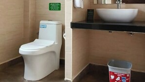 Un baño con inodoro, lavabo, espejo y cubo de basura.