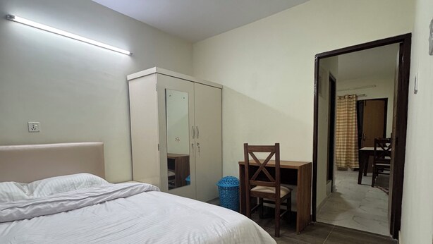 A bedroom with a bed, a wardrobe, a desk, and a mirror. - Annapurna Apartment-Khanal’s home (Kathmandu)