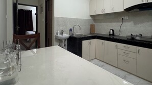 A modern kitchen with a marble countertop, white cabinets, and a built-in sink. - Annapurna Apartment-Khanal’s home (Kathmandu)