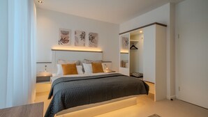 Een moderne slaapkamer met een bed, nachtkastjes, een kledingkast en wanddecoratie.