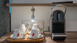 Een keukenblad met een koffiezetapparaat, een waterkoker en vier witte bekers met rode logo's.