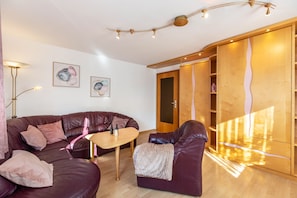 Una sala de estar moderna con un sofá de cuero, una mesa de centro de madera y una puerta corredera de madera.
