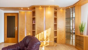 Una habitación con un sillón de cuero marrón, armarios de madera y un expositor de vidrio.