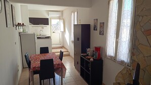 Una cocina compacta con comedor, refrigerador, lavamanos y un mueble pequeño.