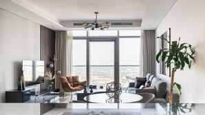 A modern living room with a large window, a round coffee table, a sofa, and a chair. - Elegant 1BR Apartment, Rooftop 360° Infinity Pool with Burj Views (Dubai)