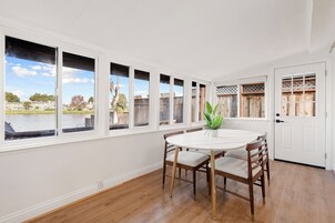 A dining area with a round table, four chairs, and a potted plant.