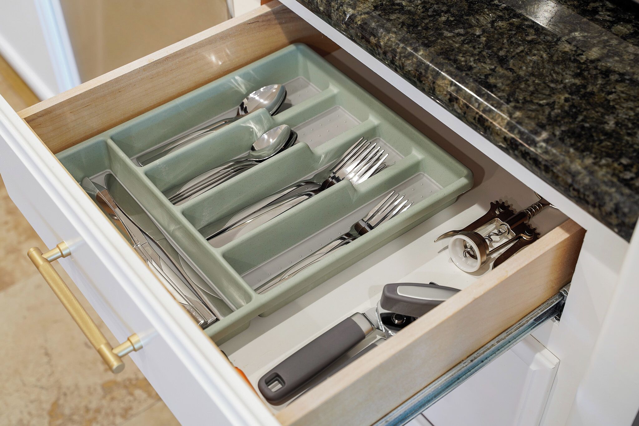 Een lade met bestek en een blikopener.