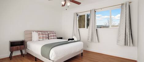 A bedroom with a bed, nightstand, and a ceiling fan.