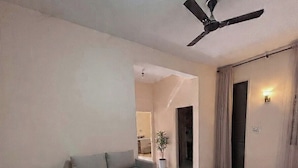 Uma sala de estar moderna com sofá, mesa de centro redonda e ventilador de teto.