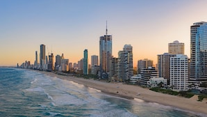 A coastal cityscape with high-rise buildings, a beach, and the ocean. - Absolute Beachfront Apartment with Direct Pool & Beach Access (Main Beach)