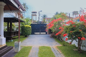 A paved pathway leading to a gated entrance, surrounded by lush greenery and flowering plants. - Ayana Beach Garden (Negombo)