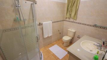 A bathroom with a glass-enclosed shower, a toilet, and a sink with a mirror.